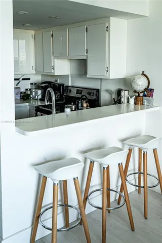 a kitchen with stainless steel appliances kitchen island granite countertop a stove a sink a refrigerator and white cabinets with wooden floor