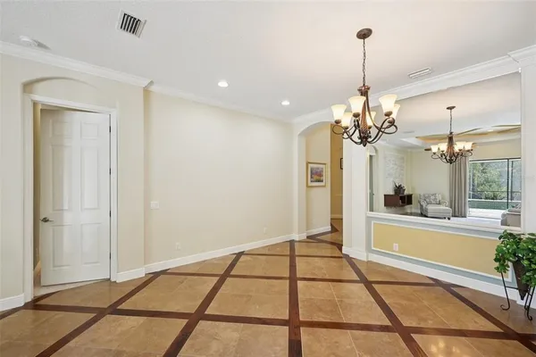 a living room with couches a chandelier and a dining table with wooden floor