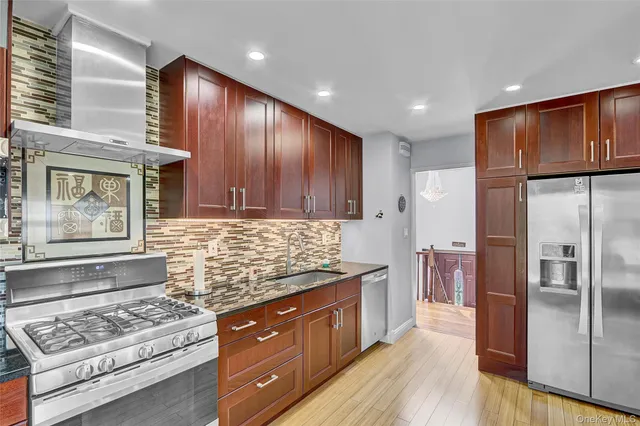 a kitchen with stainless steel appliances granite countertop a refrigerator a stove and a wooden floors