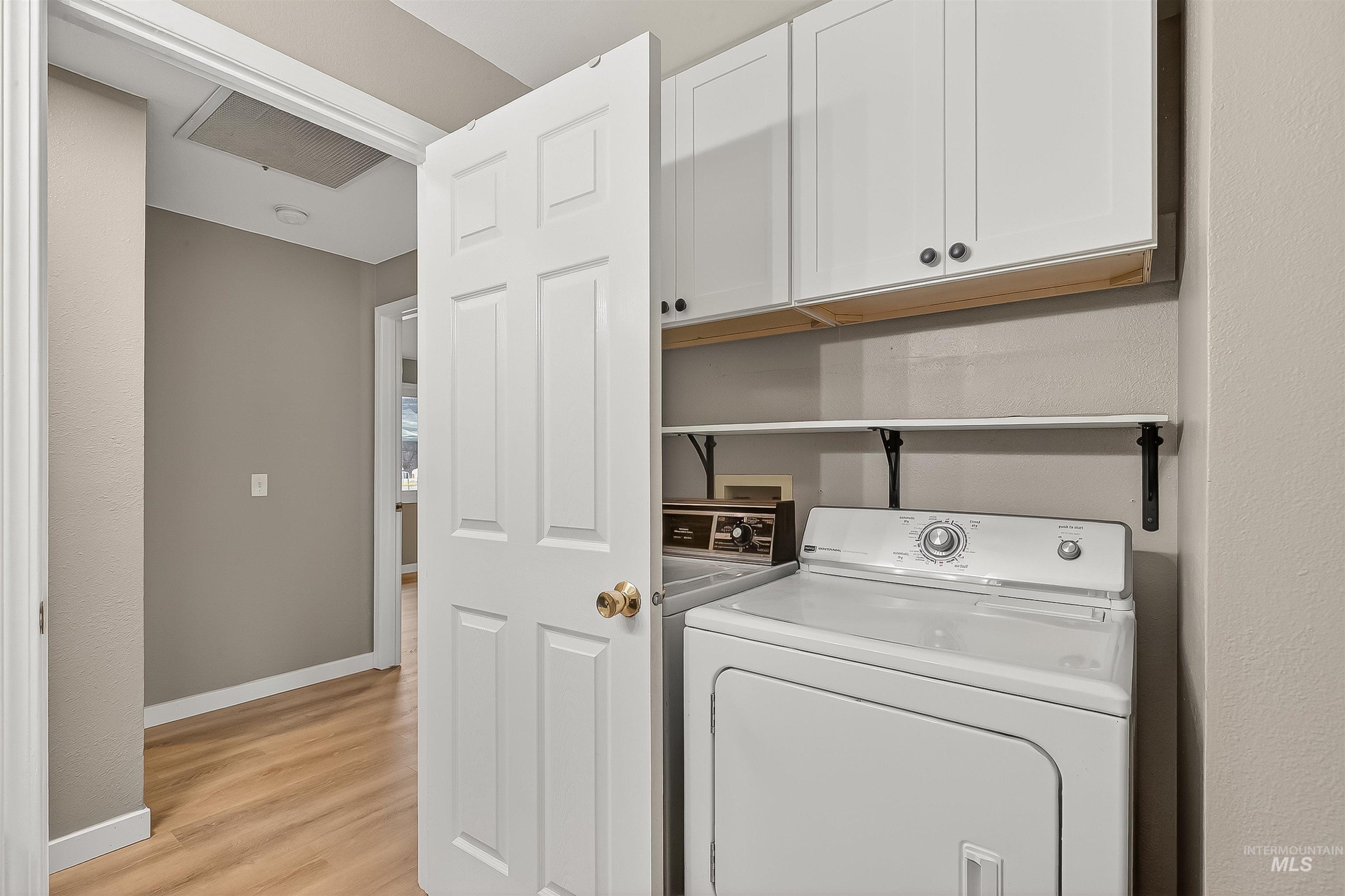 406 2nd Street Asotin, WA 99402 - Photo 15 of 37 Laundry room with cabinet space, light wood-style floors, and washing machine and dryer
