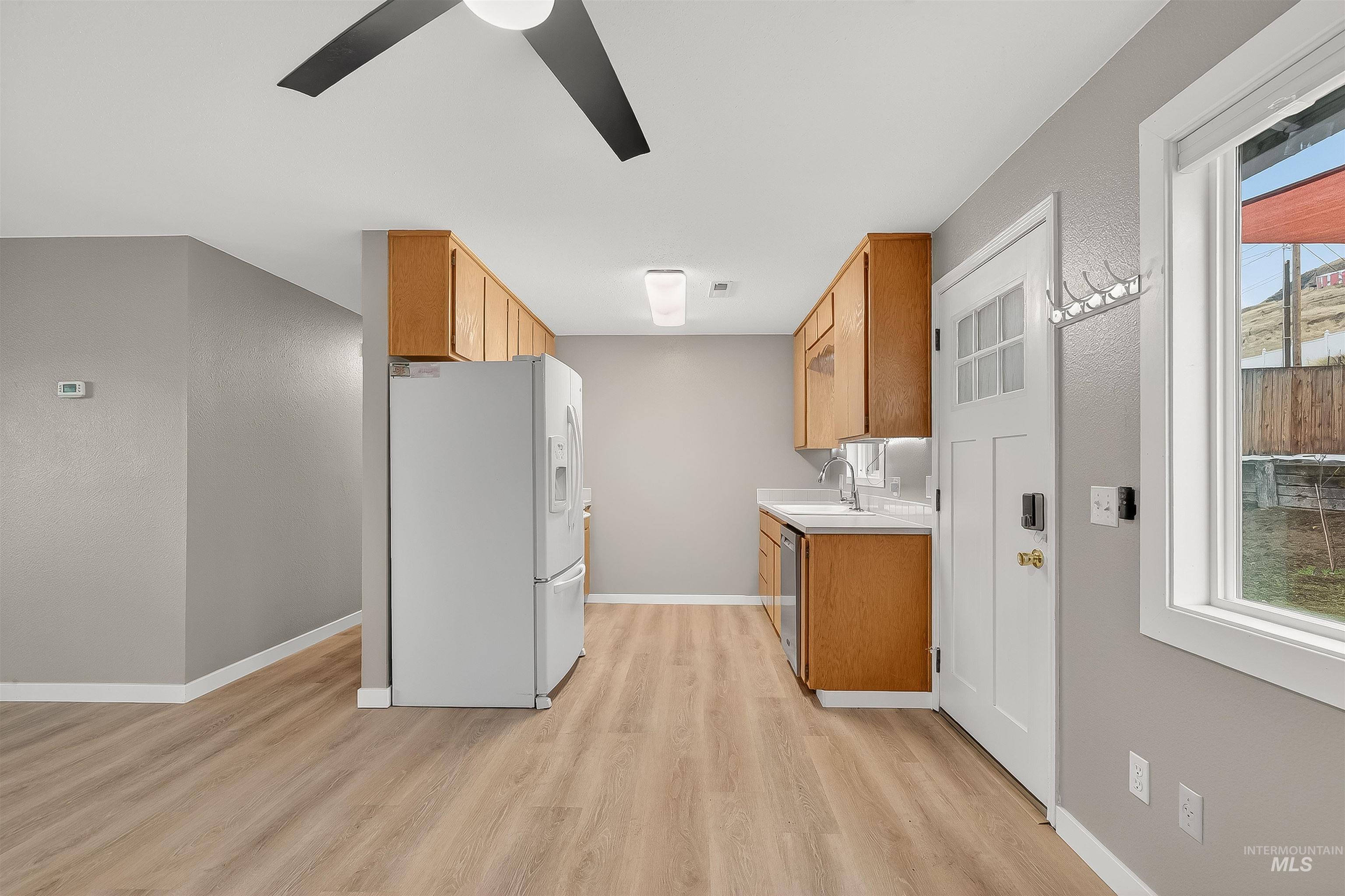406 2nd Street Asotin, WA 99402 - Photo 8 of 37 Kitchen with light countertops, white refrigerator with ice dispenser, brown cabinets, a ceiling fan, and light wood finished floors