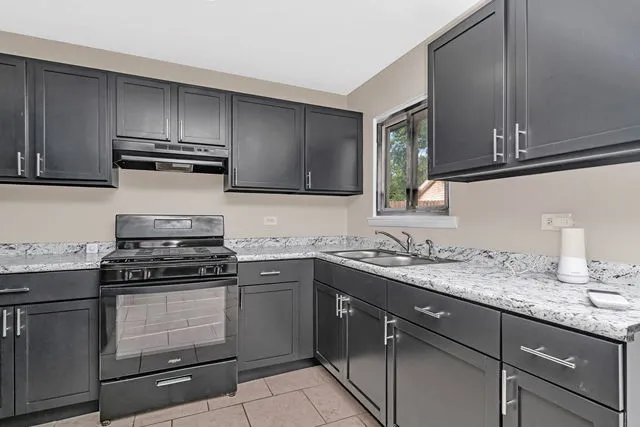 a kitchen with granite countertop stainless steel appliances a stove sink and cabinets