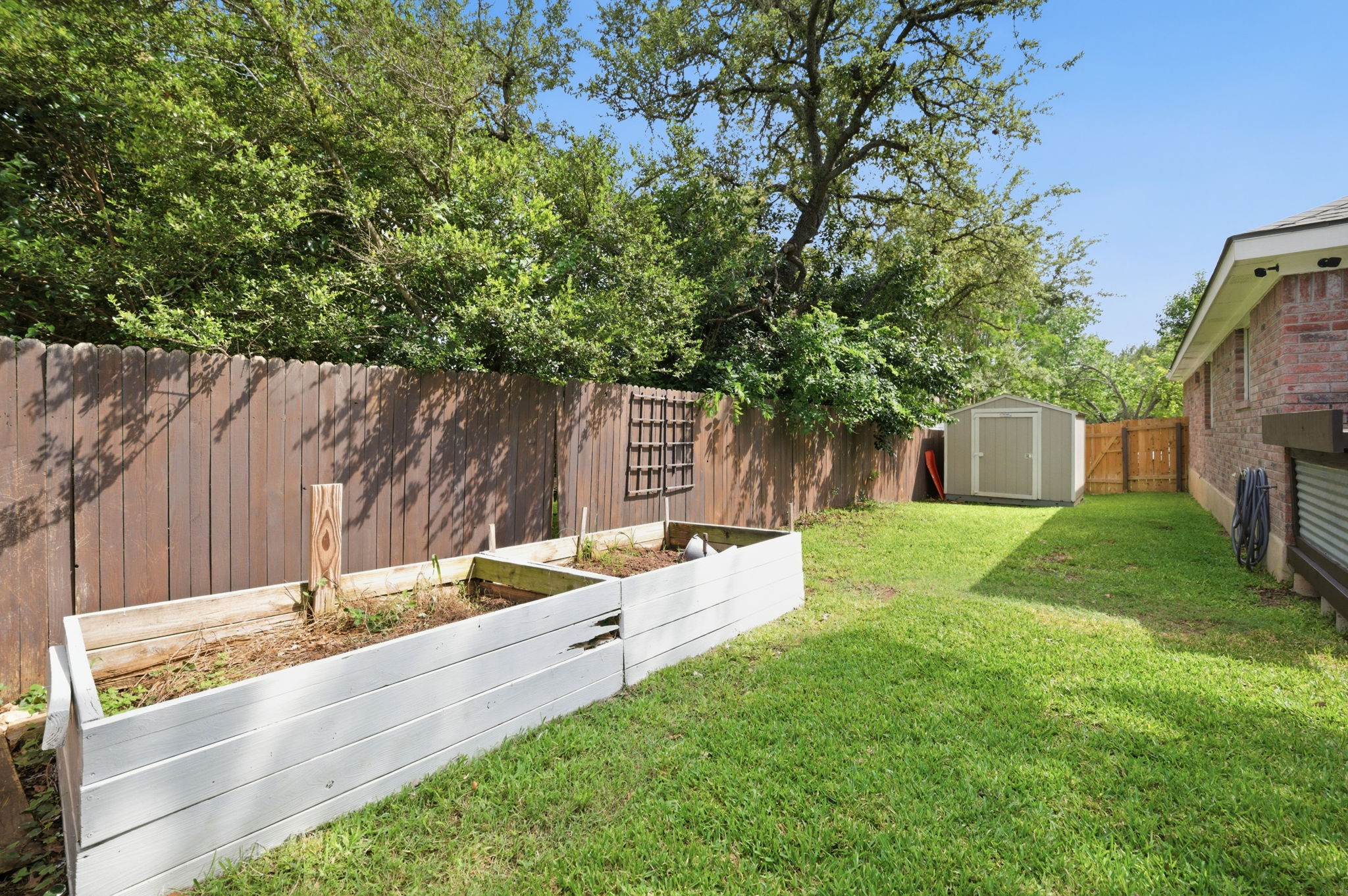 9024 Heiden Lane Austin, TX 78749 - Photo 25 of 28 Expansive backyard featuring a manicured lawn, wood privacy fencing, and a detached storage shed