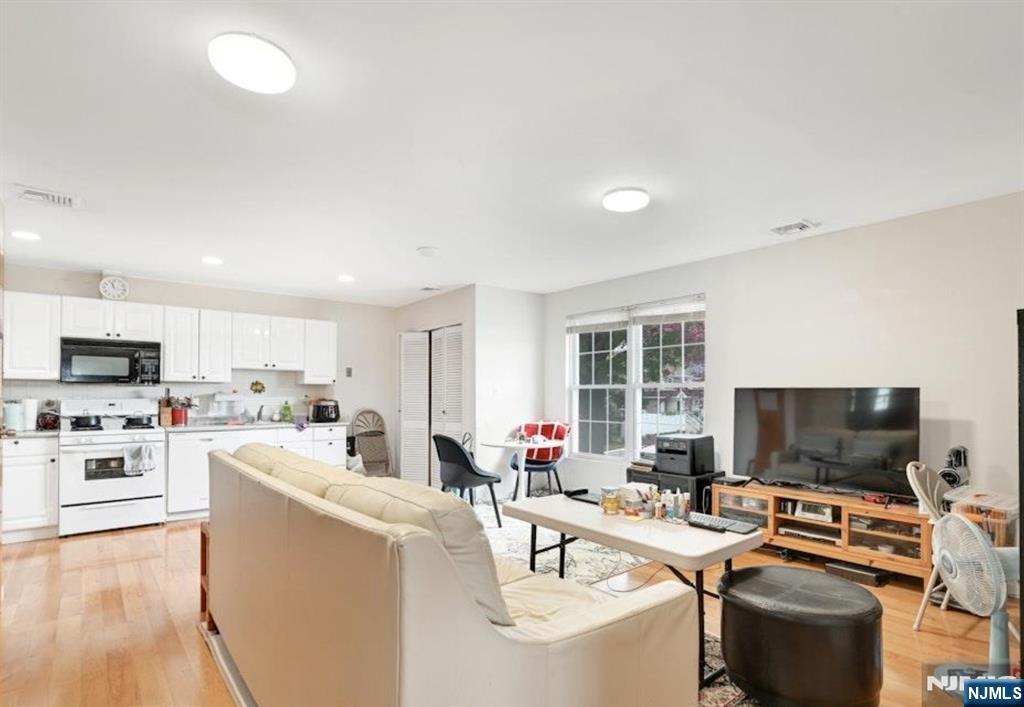 497 Oakdene Avenue Ridgefield, NJ 07657 - Photo 19 of 28 a kitchen with stainless steel appliances a stove a sink dishwasher a refrigerator and a dining table with wooden floor