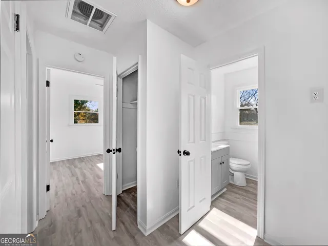 an empty room with wooden floor ceiling fan and windows