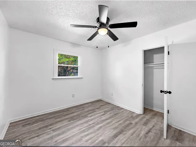 a room with a ceiling fan and wooden floor