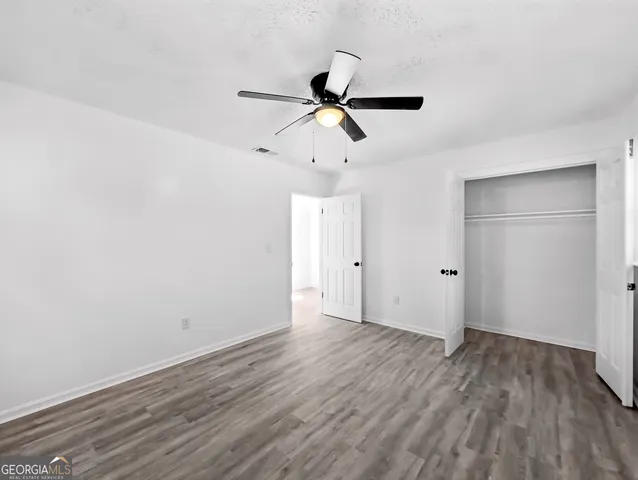 a view of empty room with wooden floor and ceiling fan