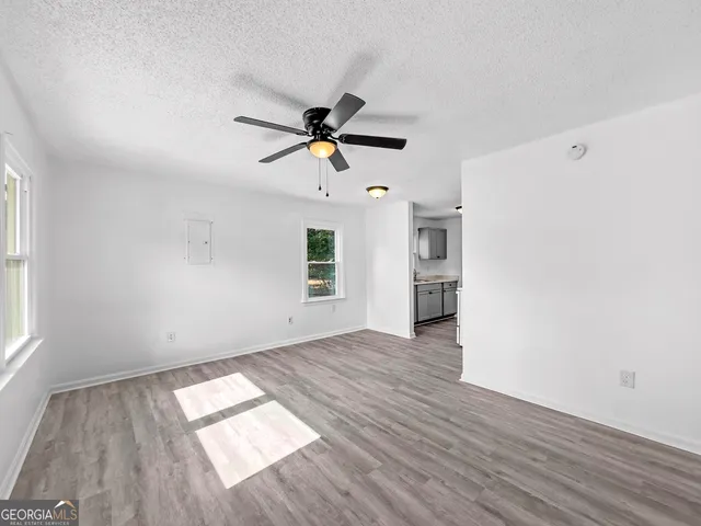 a view of empty room with wooden floor and ceiling fan