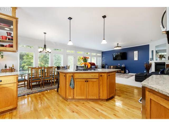 a kitchen with stainless steel appliances kitchen island granite countertop a table chairs and a refrigerator