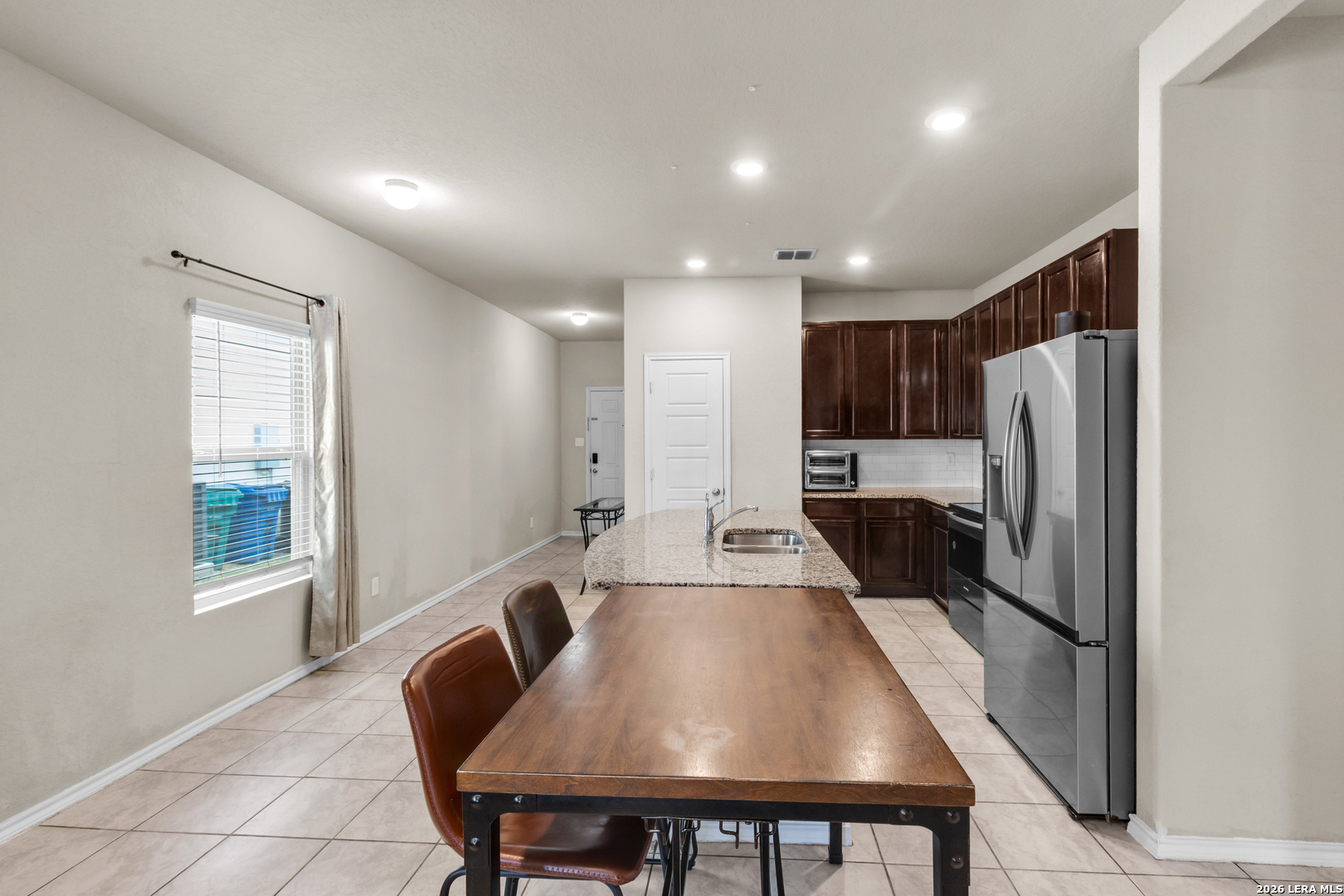 5919 Poolside Park Converse, TX 78109 - Photo 6 of 25 a kitchen with a table chairs refrigerator and microwave