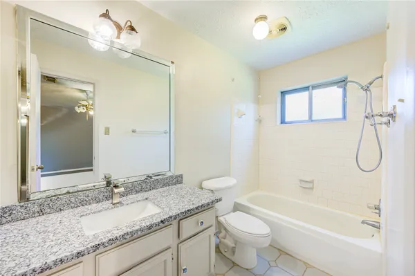 a bathroom with a granite countertop sink a toilet and bathtub
