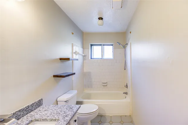 a bathroom with a granite countertop toilet a sink and bathtub