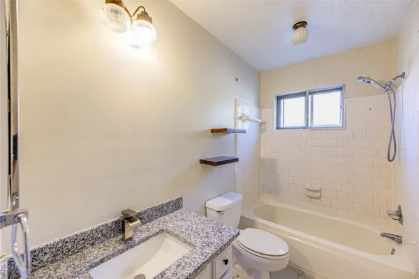 a bathroom with a granite countertop sink a toilet and shower