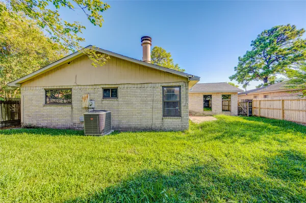 a backyard of a house with plants and large tree