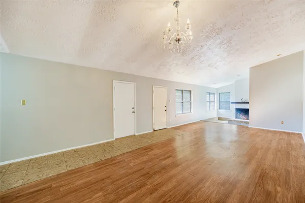 a view of empty room with wooden floor and chandelier