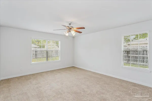an empty room with windows and fan