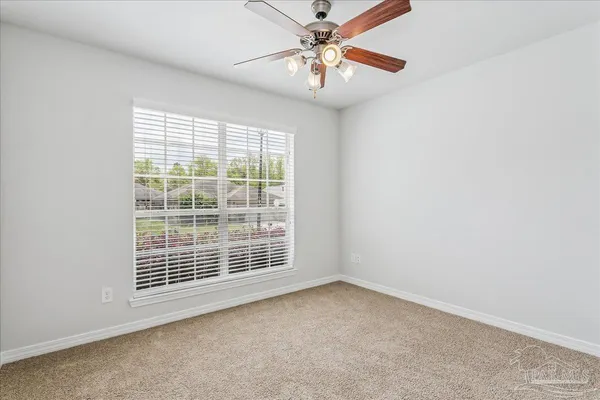 an empty room with windows and fan