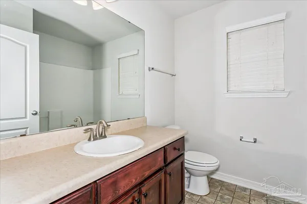 a bathroom with a granite countertop sink and a toilet