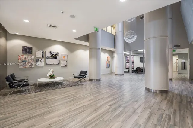 a room with lots of white furniture and wooden floor