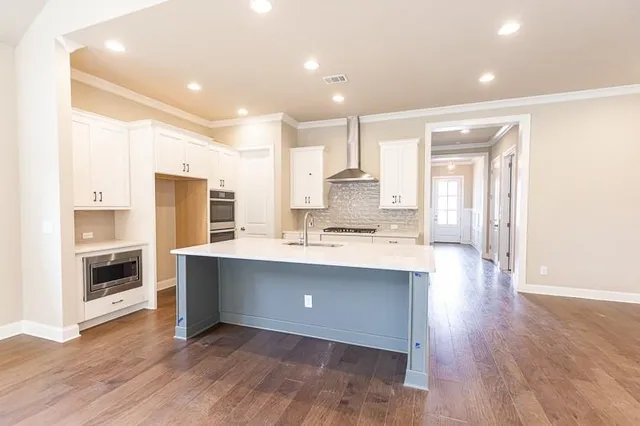 a large kitchen with a center island wooden floor and stainless steel appliances