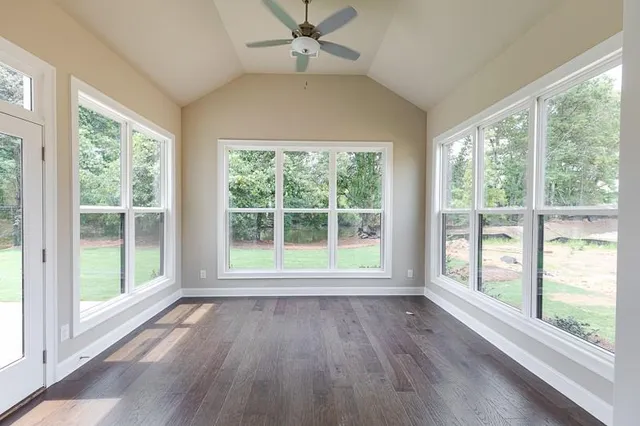 a view of an empty room with wooden floor and a window