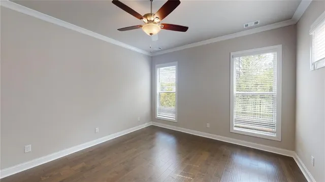 an empty room with wooden floor fan and windows