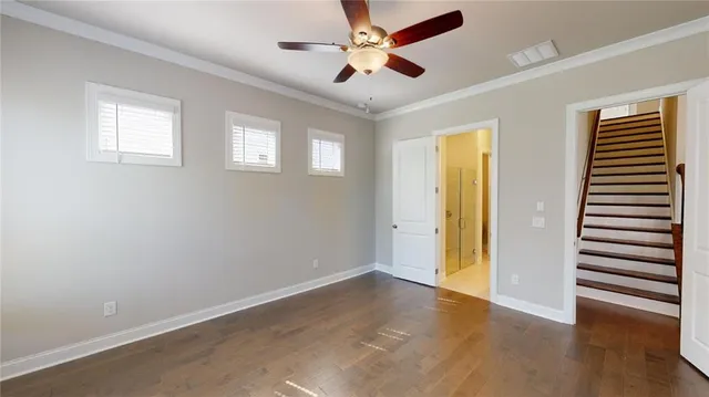 an empty room with wooden floor chandelier fan and windows