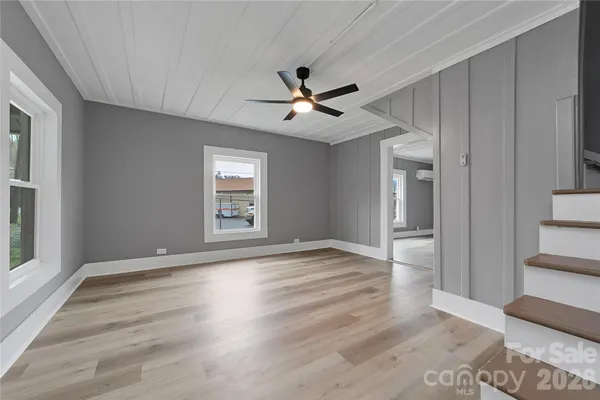 wooden floor in an empty room with a chandelier fan