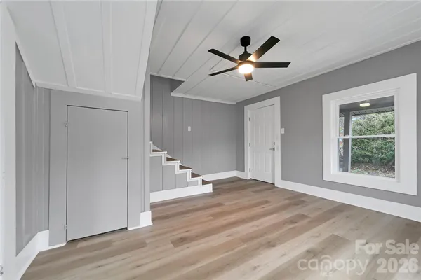 a view of an empty room with window and wooden floor
