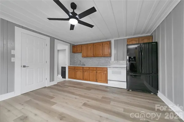 a view of a kitchen with wooden floor a ceiling fan and windows