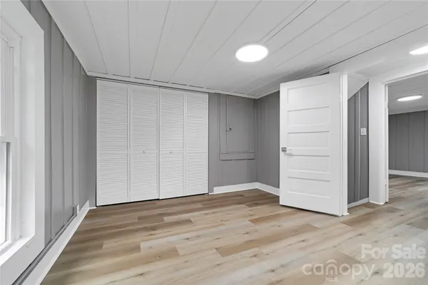 an empty room with wooden floor & closet area
