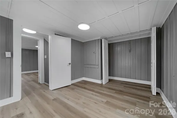 a view of an empty room with wooden floor and window