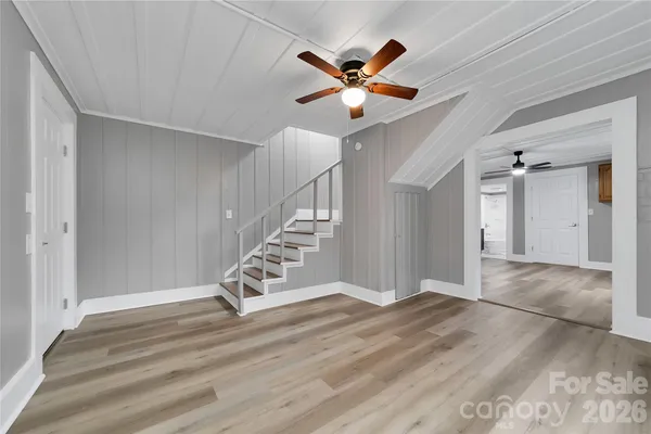 a view of an empty room with window and a chandelier fan