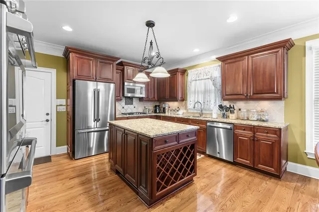 a kitchen with stainless steel appliances granite countertop a stove a refrigerator a sink dishwasher a oven and a dining table with wooden floor