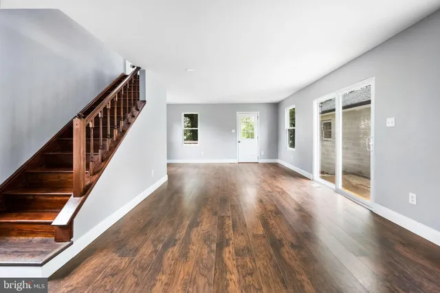a view of an empty room with wooden floor and stairs
