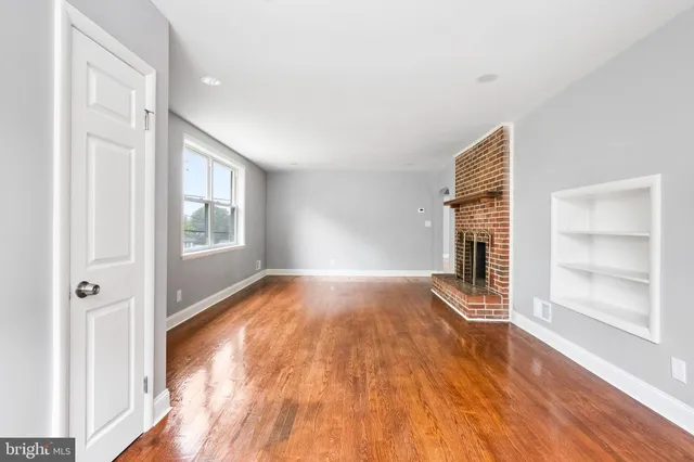 a view of empty room with wooden floor and fireplace
