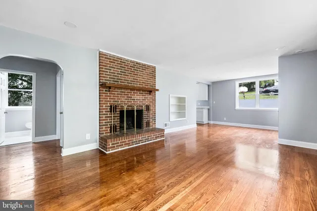 an empty room with wooden floor and fireplace