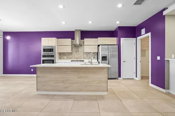 a kitchen with stainless steel appliances kitchen island granite countertop a sink and a refrigerator