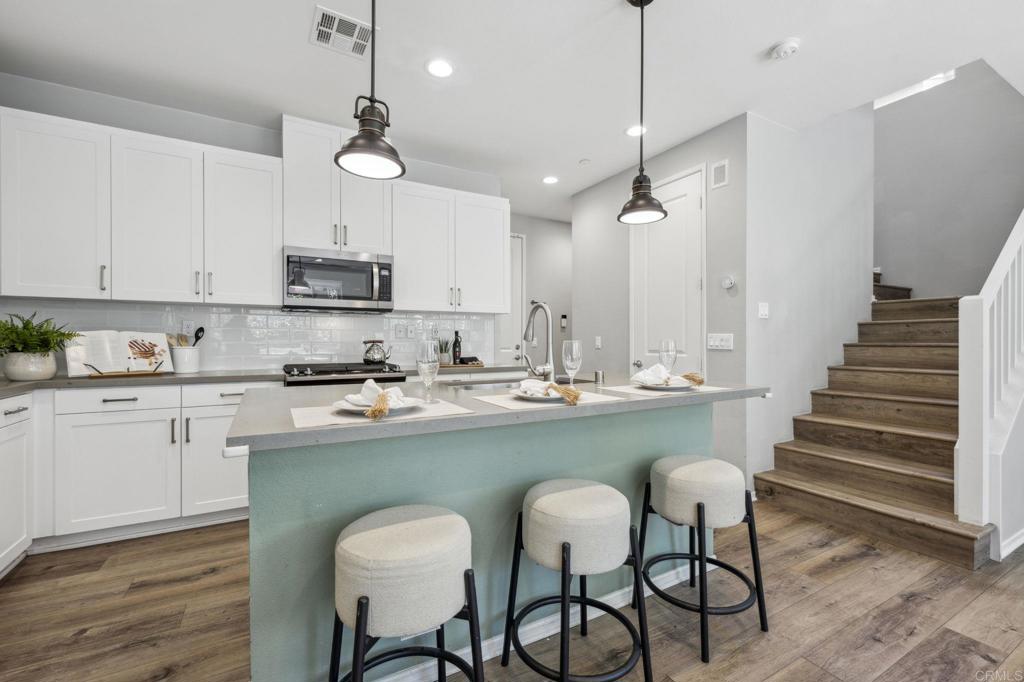 1167 Via Lucero Oceanside, CA 92056 - Photo 11 of 54 a kitchen with stainless steel appliances granite countertop a sink a stove a refrigerator and island with wooden floor