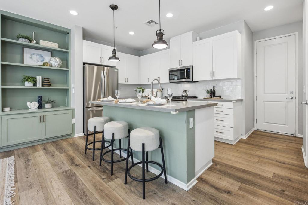 1167 Via Lucero Oceanside, CA 92056 - Photo 13 of 54 a kitchen with stainless steel appliances a table chairs refrigerator and cabinets