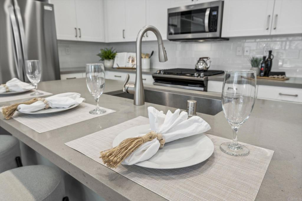 1167 Via Lucero Oceanside, CA 92056 - Photo 14 of 54 a kitchen with a sink dishwasher a stove and a microwave with wooden floor