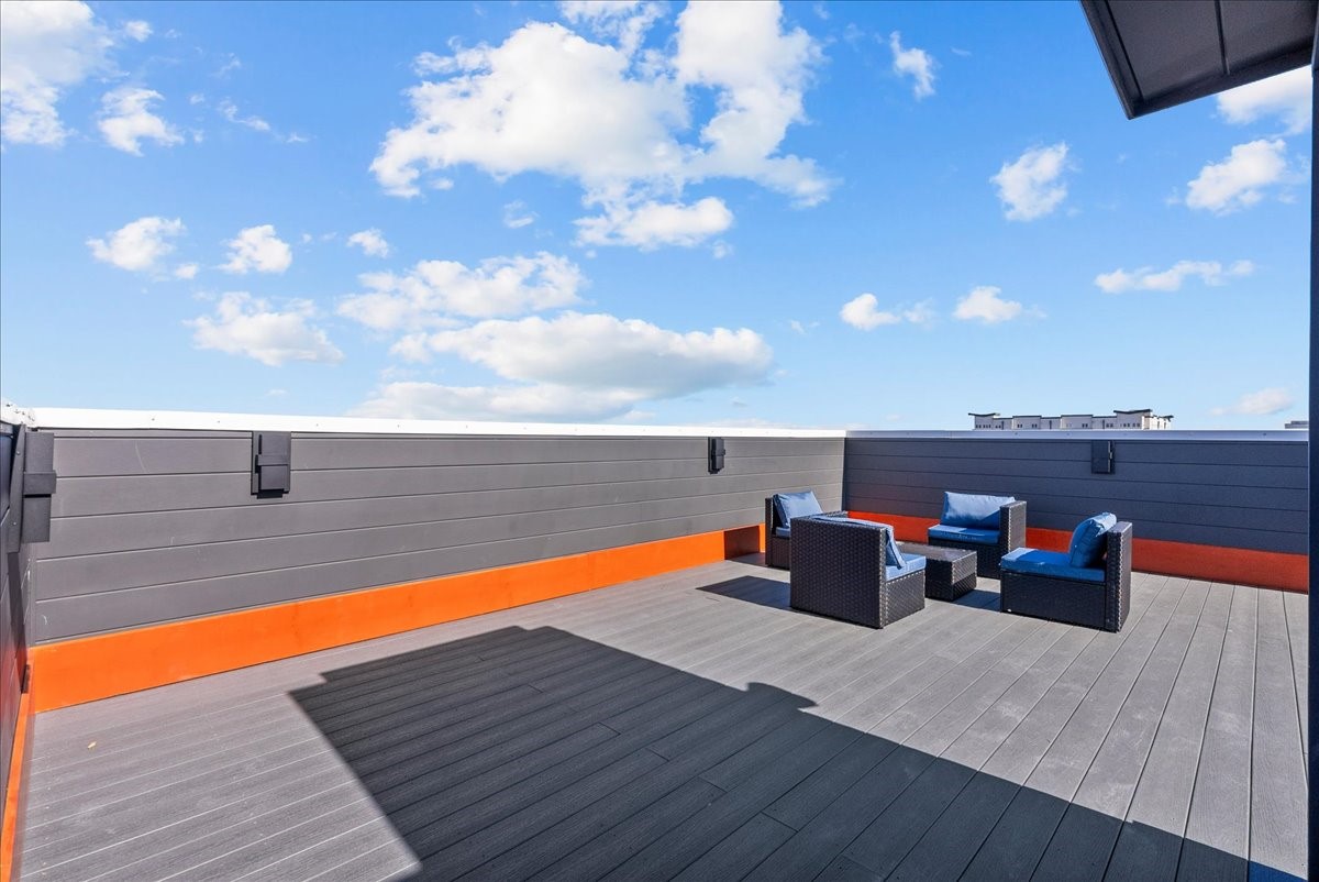 516 Reinerman Street Houston, TX 77007 - Photo 7 of 42 This photo showcases a spacious rooftop terrace with modern outdoor seating, featuring weather-resistant furniture. The area is enclosed by sleek, dark paneling and offers a clear view of a bright blue sky, ideal for relaxation or entertaining guests.