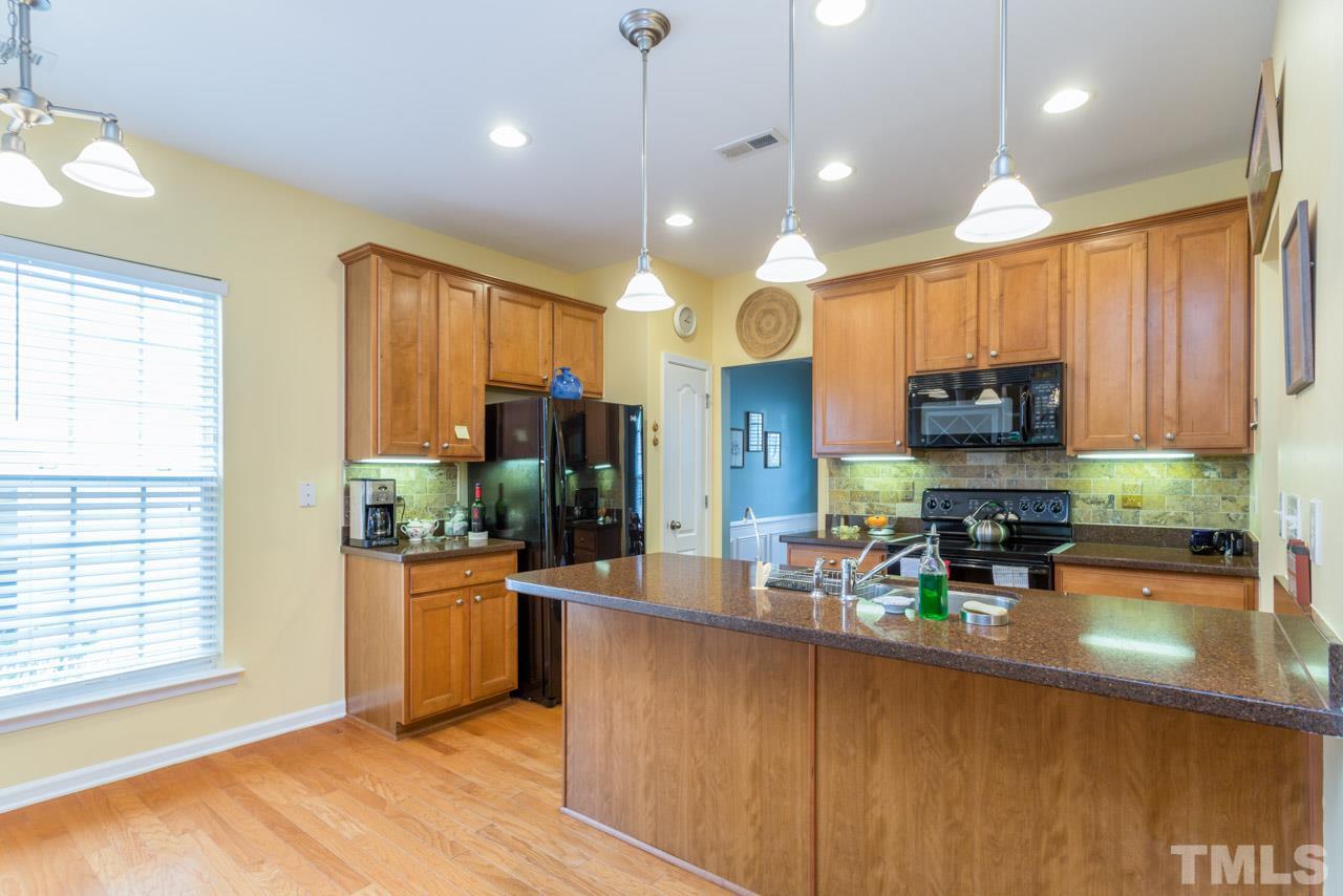 3406 Cathedral Bell Road Raleigh, NC 27614 - Photo 8 of 25 a kitchen with stainless steel appliances kitchen island granite countertop a stove top oven a sink a dining table and chairs with wooden floor