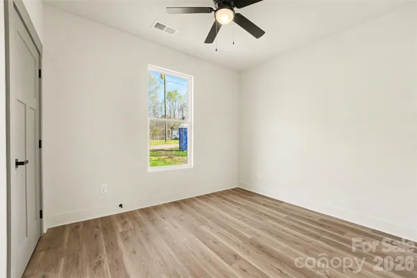 a view of empty room with wooden floor and fan