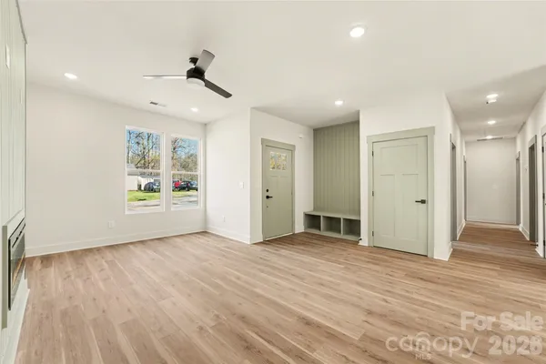 a view of an empty room with wooden floor and a ceiling fan