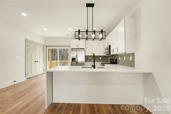 a view of a kitchen with living room and wooden floor
