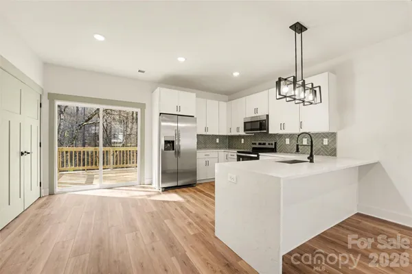 a view of a kitchen with stainless steel appliances granite countertop a refrigerator oven a a sink and a dishwasher with wooden floor