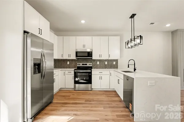 a kitchen with stainless steel appliances kitchen island granite countertop a refrigerator a stove oven a sink with island and chairs