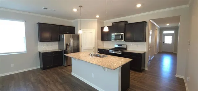 a large kitchen with a center island wooden floor stainless steel appliances and cabinets