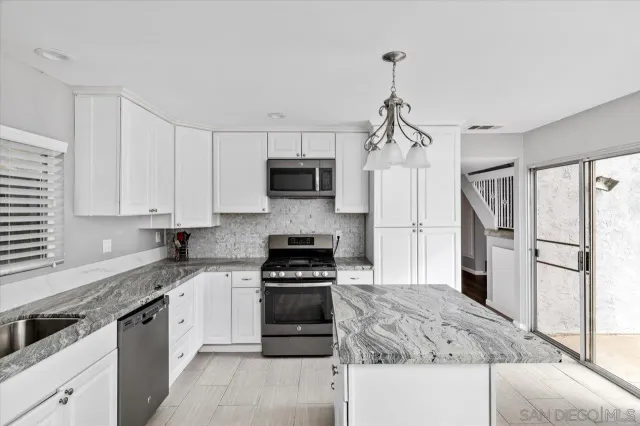 a kitchen with kitchen island granite countertop a refrigerator oven a sink and dishwasher